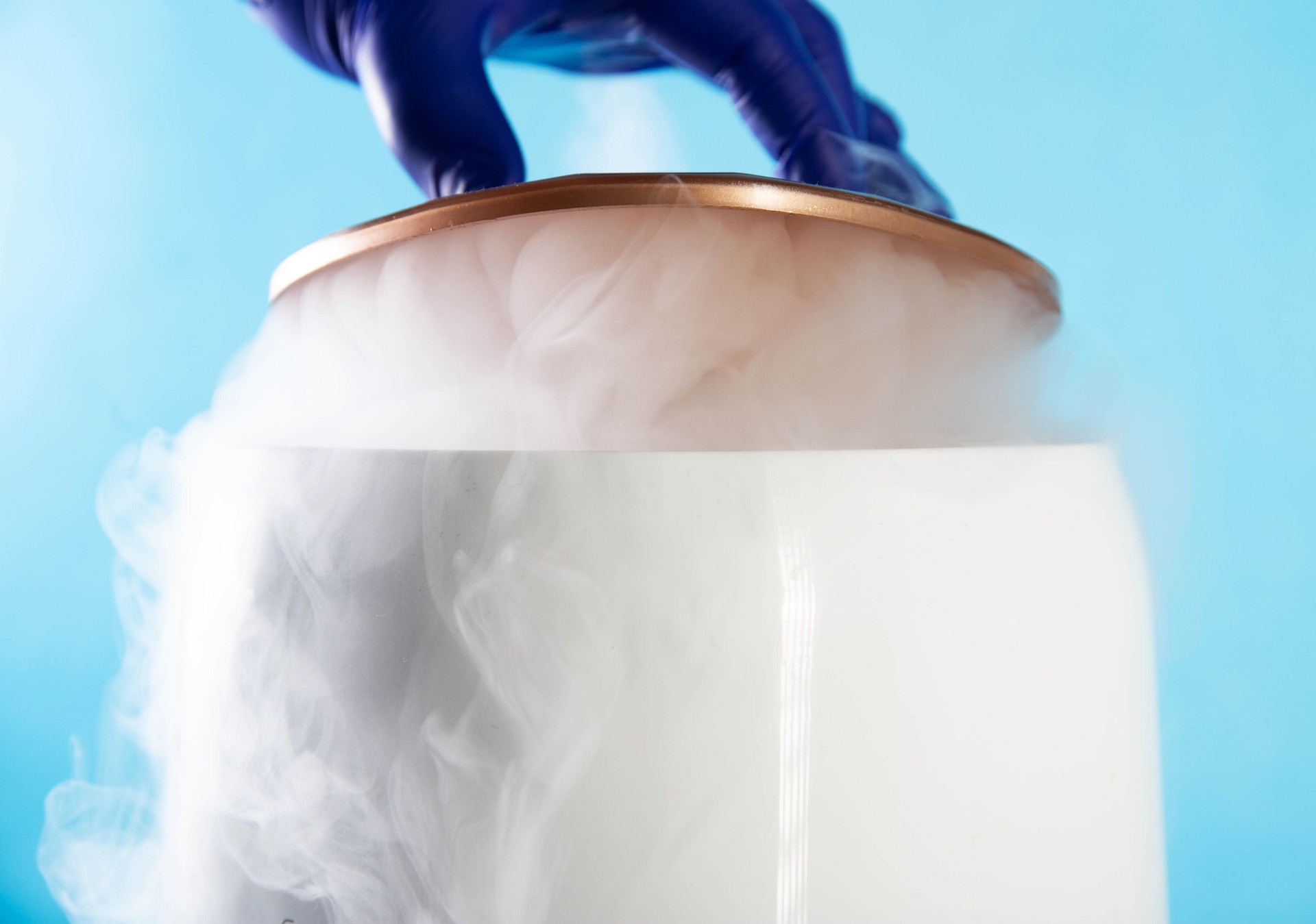 A doctor's hand in a medical glove opens a container with liquid nitrogen to store organs during transplantation. Cryotherapy, cryobank